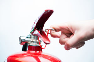 Hand pulling pin of fire extinguisher