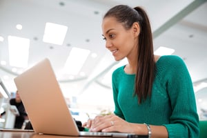 Portrait of a happy female student using laptop computer in university